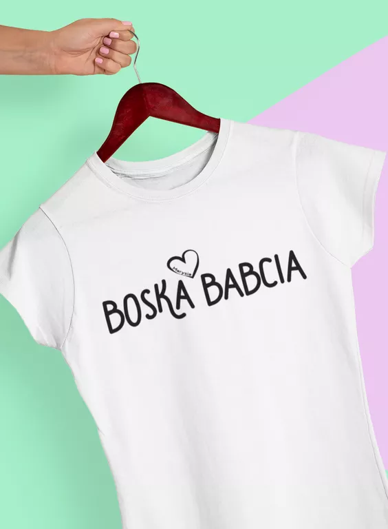 Biała koszulka damska z nadrukiem Boska Babcia wisząca na drewnianym wieszaku