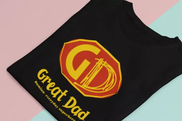 Czarna koszulka z nadrukiem Great Dad i personalizacją złożona na dwukolorowym tle