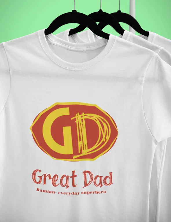 Biała koszulka personalizowana dla taty wisząca na czarnym wieszaku