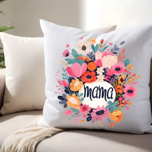Poduszka dekoracyjna z kolorowym, kwiatowym wieńcem i napisem „Mama” na białym tle, umieszczona na beżowej sofie w jasnym wnętrzu.
