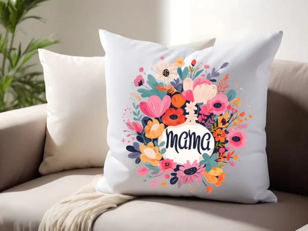 Poduszka dekoracyjna z kolorowym, kwiatowym wieńcem i napisem „Mama” na białym tle, umieszczona na beżowej sofie w jasnym wnętrzu.
