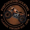 Grafika koszulki 'Pięćdziesięcioletni Klasyk EST. 1975' z brązowym motocyklem vintage, w okręgu z postarzaną teksturą.