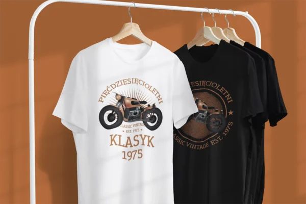 Dwie męskie koszulki 'Pięćdziesięcioletni Klasyk EST. 1975' w kolorach białym i czarnym, zawieszone na wieszakach.