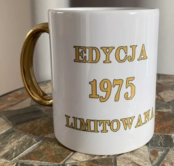 Personalizowany biały kubek ceramiczny ze złotym uchem i złotym napisem "EDYCJA 1975 LIMITOWANA".