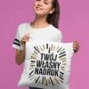 Uśmiechnięta kobieta trzymająca białą poduszkę z napisem "Twój Własny Nadruk", prezentująca personalizowany produkt.