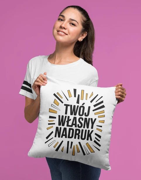 Uśmiechnięta kobieta trzymająca białą poduszkę z napisem "Twój Własny Nadruk", prezentująca personalizowany produkt.