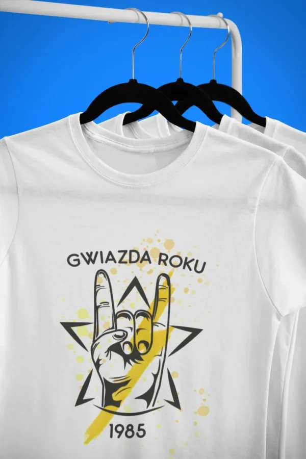 Biała koszulka z rockowym nadrukiem i żółtymi kropkami farby na wieszaku