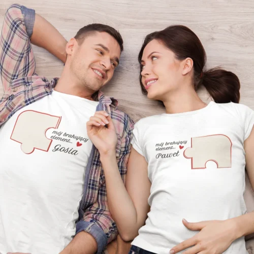Szczęśliwa para leżąca na podłodze w białych koszulkach z motywem puzzla patrząca na siebie