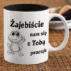 czarny ceramiczny kubek z napisem Zajebiście nam się z Tobą pracuje oraz ilustracją uśmiechniętej żaby na marmurowym blacie.