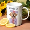 Biały ceramiczny kubek z napisem Birthday Girl i grafiką psa w prezencie, stojący na drewnianym stole obok cytryn i słoneczników.