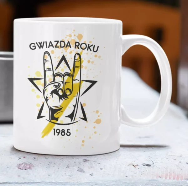 Biały ceramiczny kubek z grafiką dłoni w geście rockowym, żółtą gwiazdą i personalizowaną datą 1985