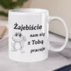 Biały ceramiczny kubek z napisem Zajebiście nam się z Tobą pracuje oraz ilustracją uśmiechniętej żaby na marmurowym blacie.